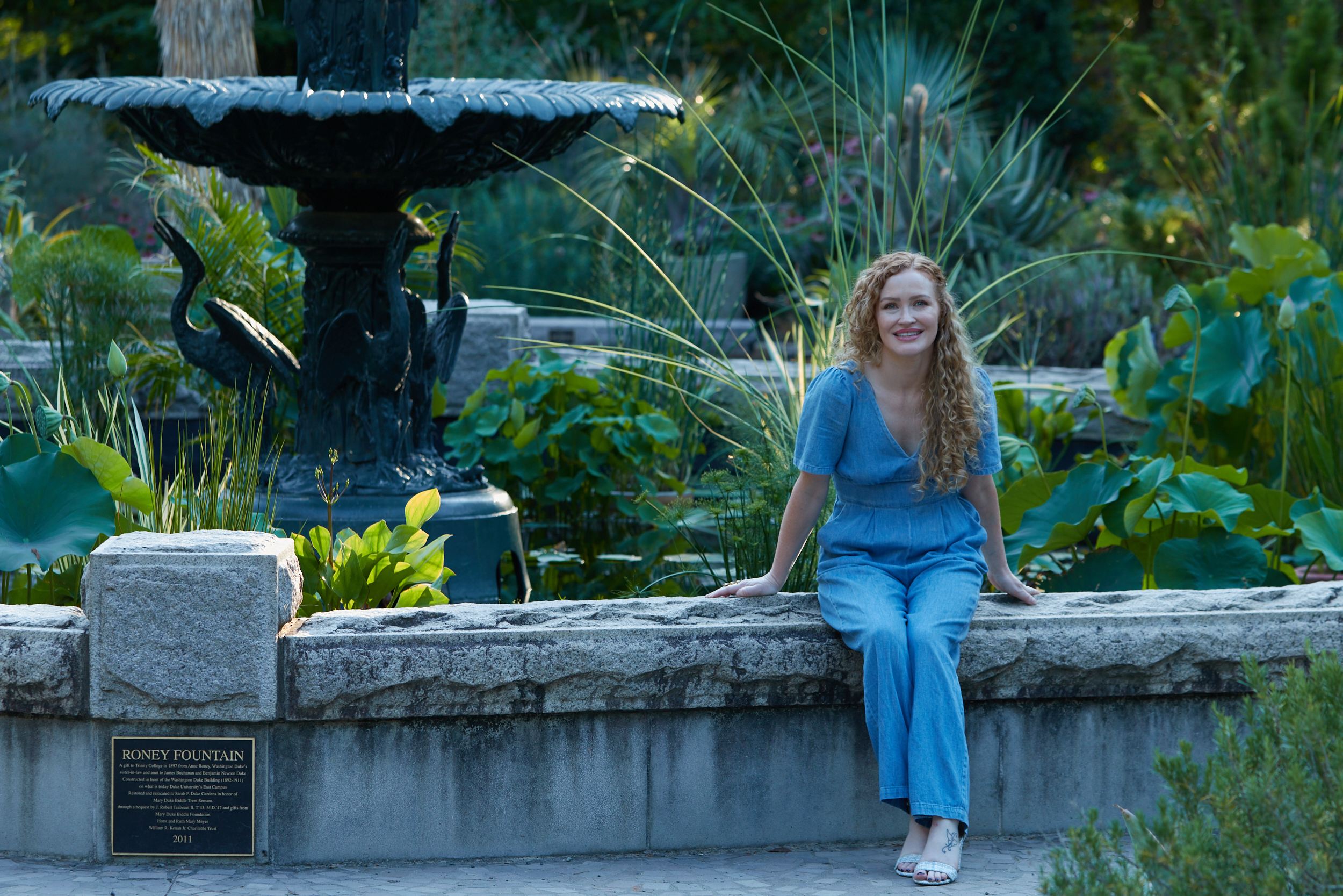 Carrie Davidson seated at the edge of the fountain, smiling at the camera